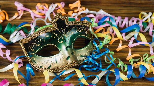 Close-up of a carnival mask with colorful streamers on wooden desk