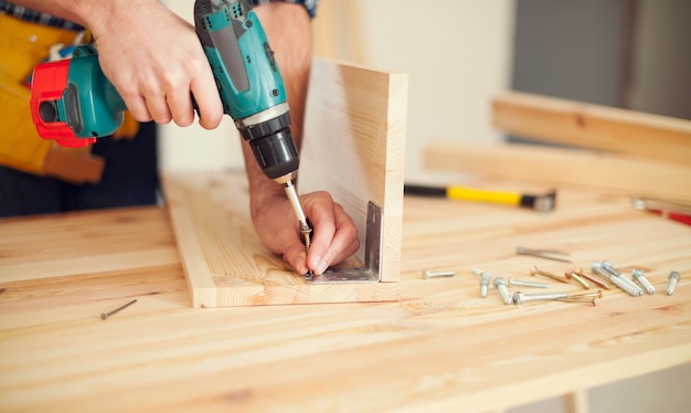 Close up of carpenter working with drill