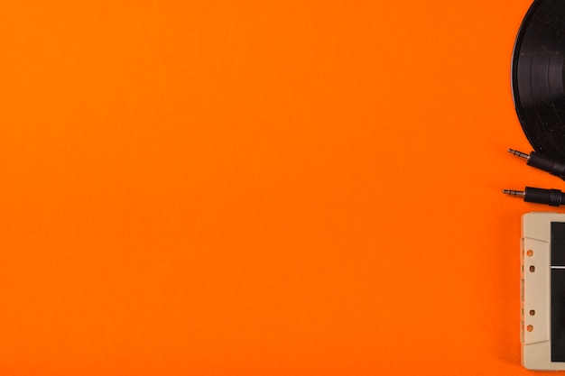 Free Photo close-up of cassette tape and vinyl record on an orange background