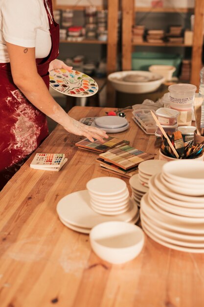 Close-up of ceramics palettes with stack of plates on wooden table