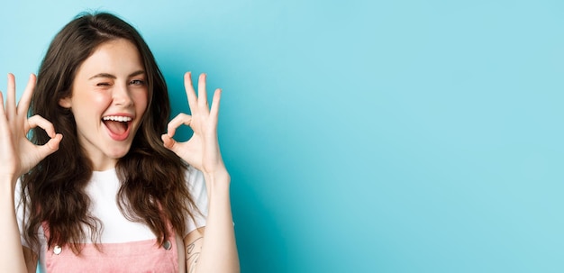 Close up of cheerful caucasian woman agree and say yes make alright okay sign and winking assuringly