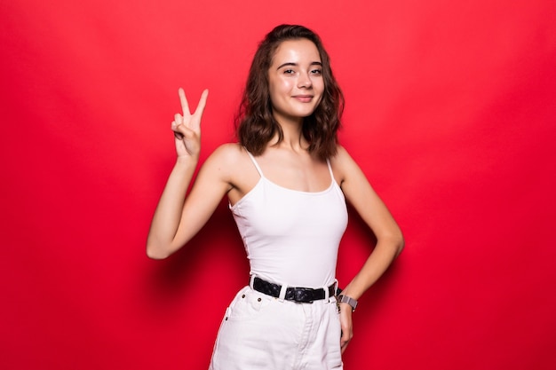 Close up of a cheery stylish girl wearing hat showing peace gesture