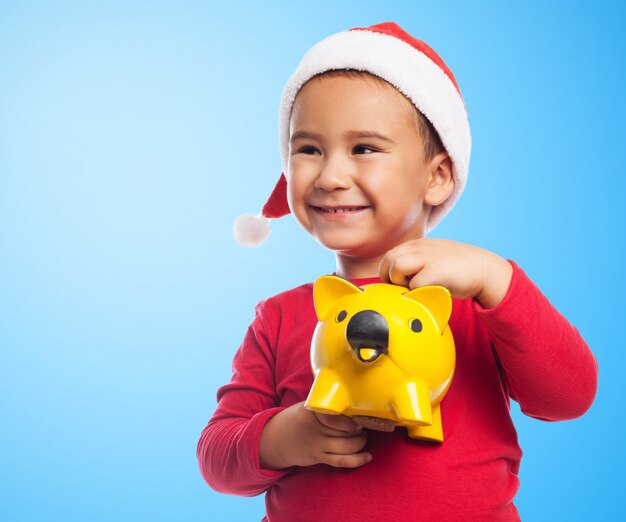 Close-up of child holding a piggybank with blue background