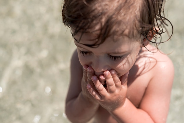 Close up child with eyes closed playing in water