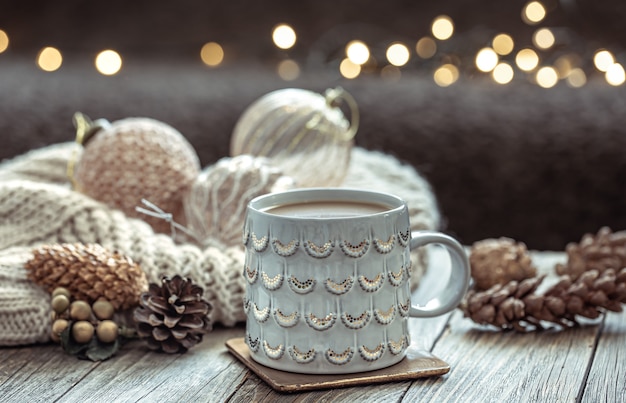 Close up of Christmas cup and festive decor on blurred dark background with bokeh.