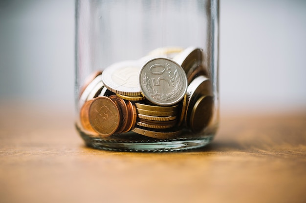 Close-up of collected coins in the glass jar on table