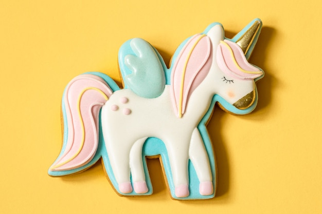 Free photo close-up of colorful gingerbread in the shape of a unicorn on a yellow surface.