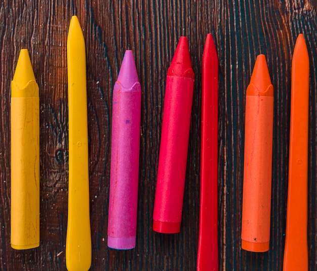 Close-up of colorful wax crayons over wooden textured plank