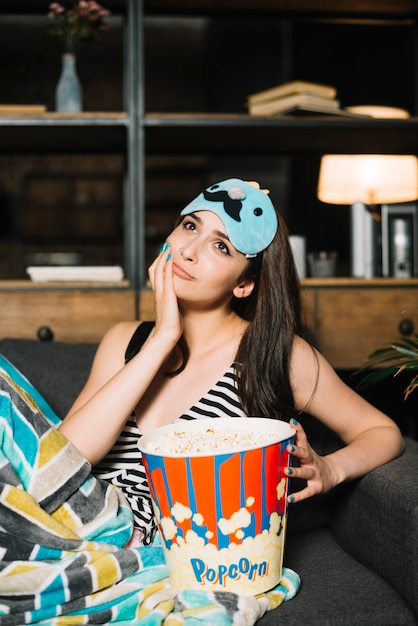 Close-up of a contemplated young woman with popcorn