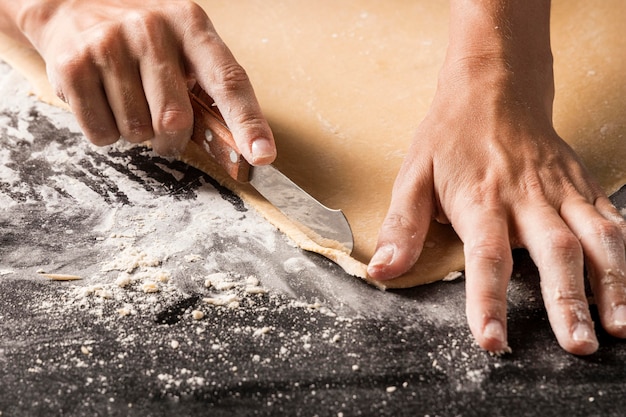 Free photo close-up cook cutting dough