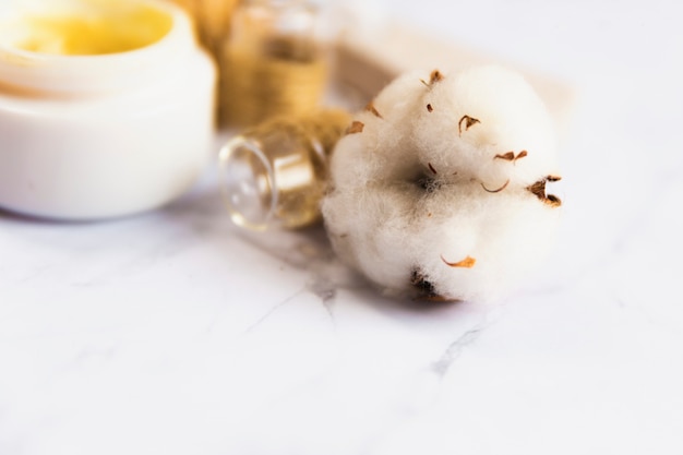 Close-up of cotton flower with cream bottle