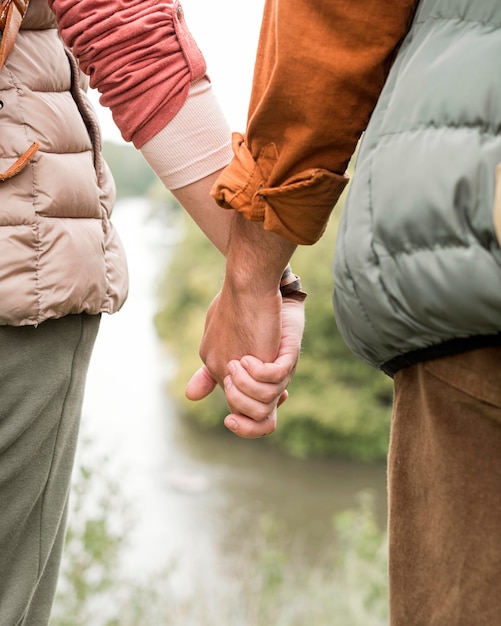 Close-up couple holding hands near river