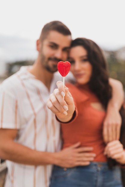 Close-up couple holding heart lollipop