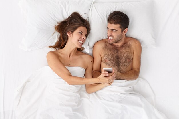 Close up on couple lying in bed under white blanket