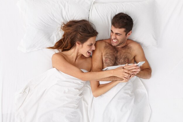 Close up on couple lying in bed under white blanket