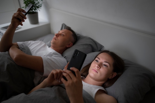 Close up on couple on phones in bedroom