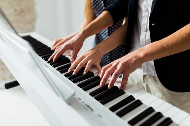 Close-up of couple's hand playing piano keyboard