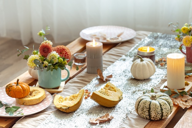 Free photo close-up of cozy decor details of a festive autumn dining table with pumpkins, flowers and candles.