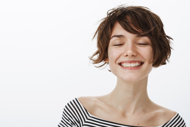 Close-up of cute hipster woman smiling carefree, close eyes and imaging something beautiful