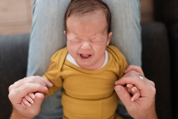 Free photo close-up dad holding yawning baby on his legs