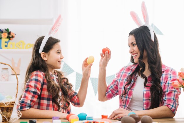 Close-up of a daughter and her mother showing easter eggs to each other