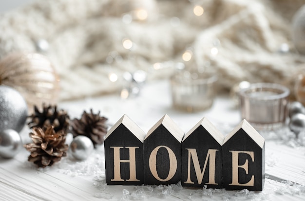 Close-up of decorative wooden word home on blurred background with details of Christmas holiday decor.