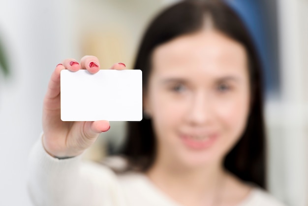 Free photo close-up of defocus young businesswoman showing white visiting card