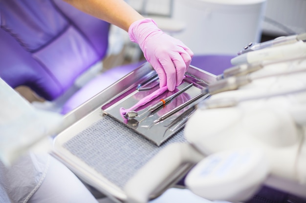 Close-up of a dentist's hand arranging dental tools on tray