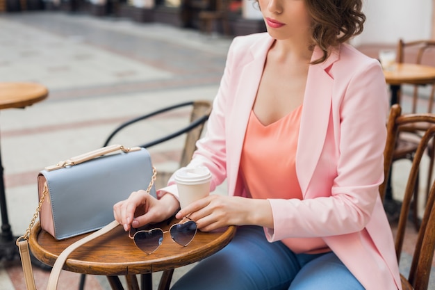 Free Photo close up details of accessories of stylish woman sitting in cafe drinking coffee, sunglasses, handbag, spring summer fashion trend, elegant style