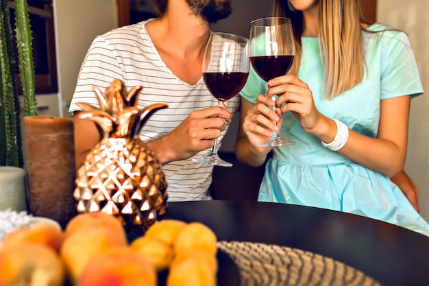 Free photo close up details of romantic evening of pretty couple drinking red wine end enjoying time together, modern interior and trendy elegant clothes.