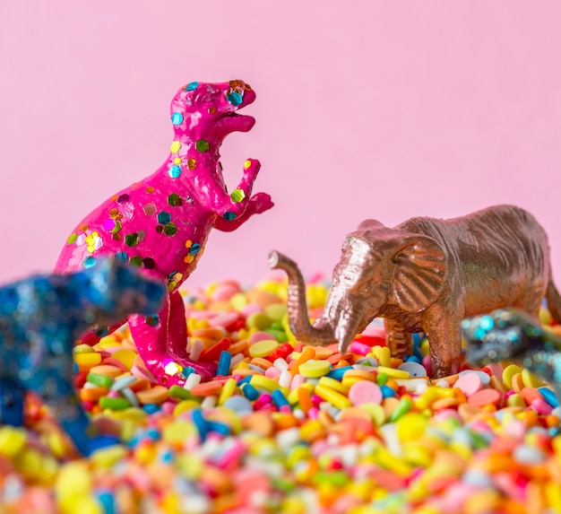 Free photo close up of dinosaurs and animal figure toys on sweet candy sprinkles