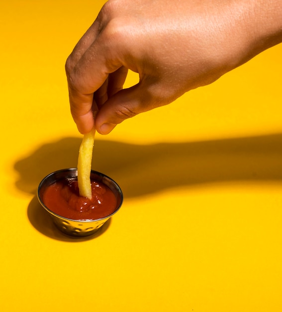 Free photo close-up dipping french fry in ketchup