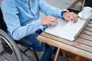 Free photo close-up disabled man typing on laptop