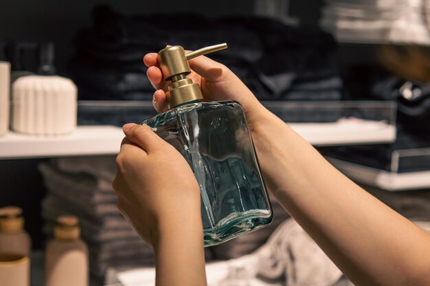 Close up a dispenser for liquid soap in female hands in the store