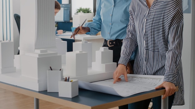 Free photo close up of diverse team of women working on blueprints design in office. multi ethnic architects using industrial print on table to plan construction layout for architecture project.