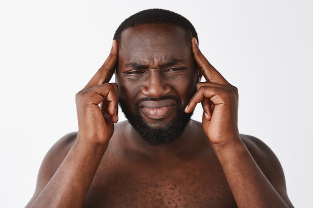 Close-up of dizzy young guy posing against the white wall