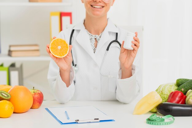 Close-up doctor holding up half an orange