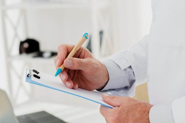 Free photo close-up of doctor writing on clipboard