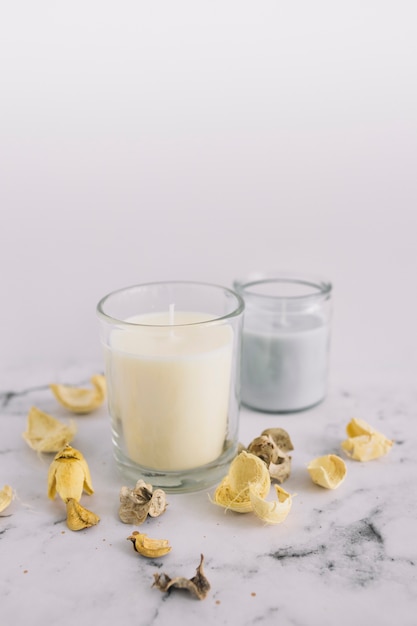 Free Photo close-up of dry pods and candle in candleholder on marble surface