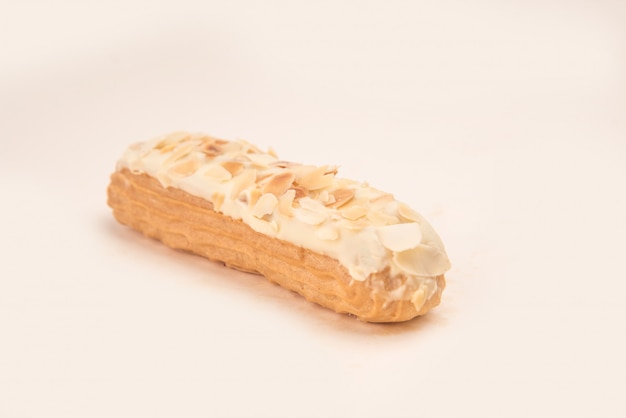 Free photo close up of eclair with white cream and nuts isolated over white