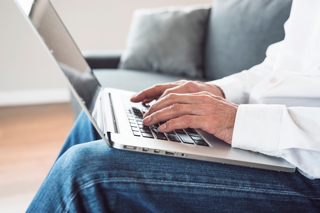 Close-up of an elderly man typing on laptop