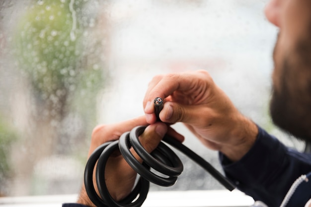 Close-up of electrician's hand holding black electric cable