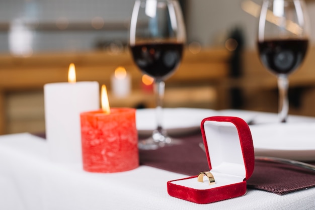 Close-up of engagement ring and burning candles