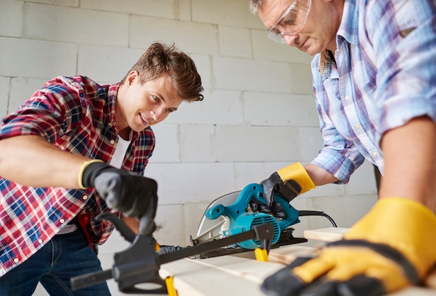 Free photo close up on experienced carpenter and his younger employee