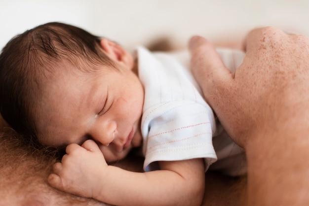 Close-up father holding baby on his chest