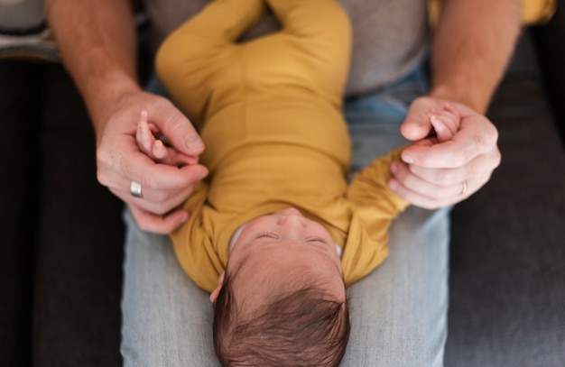 Free photo close-up father holding baby on his legs