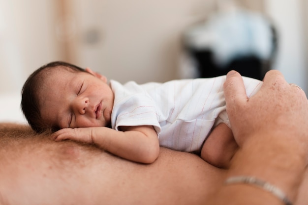 Free photo close-up father holding sleepy baby on his chest