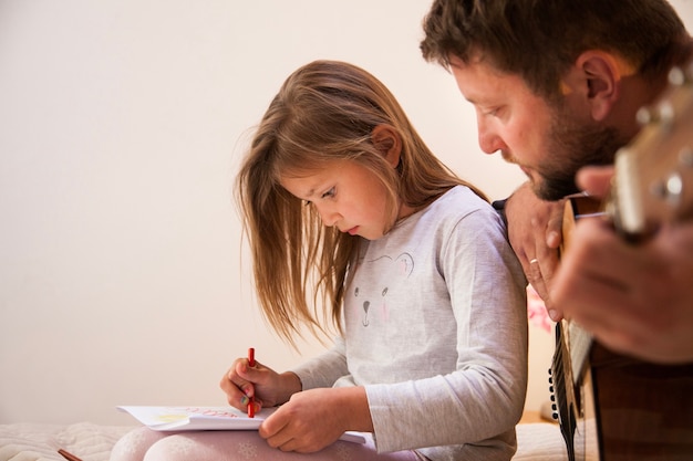 Close-up of father looking at his daughter draw