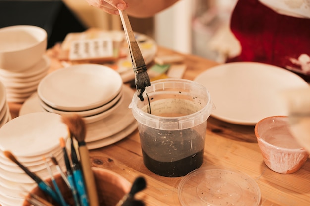 Free photo close-up of female artisan painting the ceramic plate with paintbrush