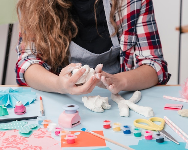 Free photo close-up of a female artist making letter with white clay